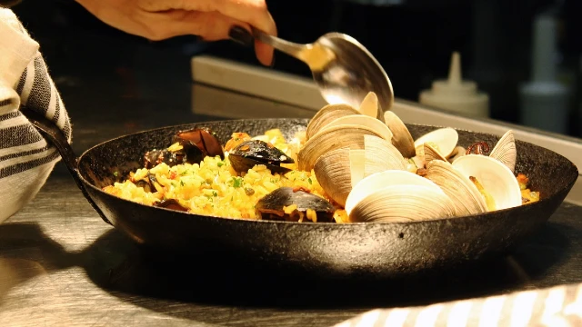 Seafood paella type dish in a dark cast iron pan.