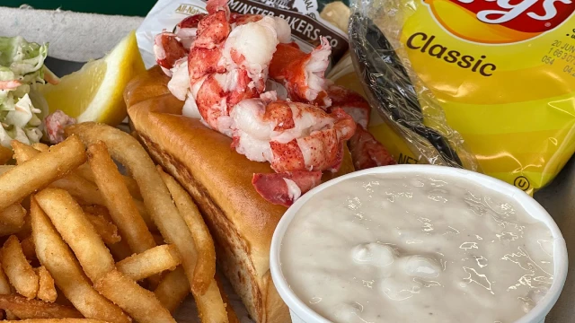 A lobster roll with french fries, chowder and chips.
