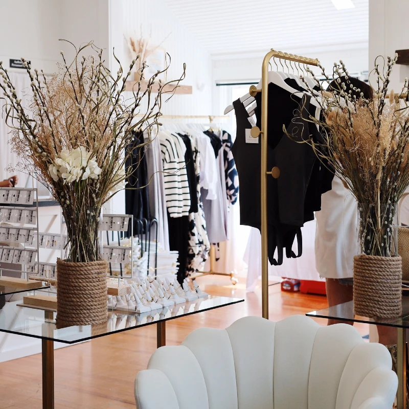 A view of the interior of the Bobbles & Lace shop with jewelry, clothes on hangers and a white couch.