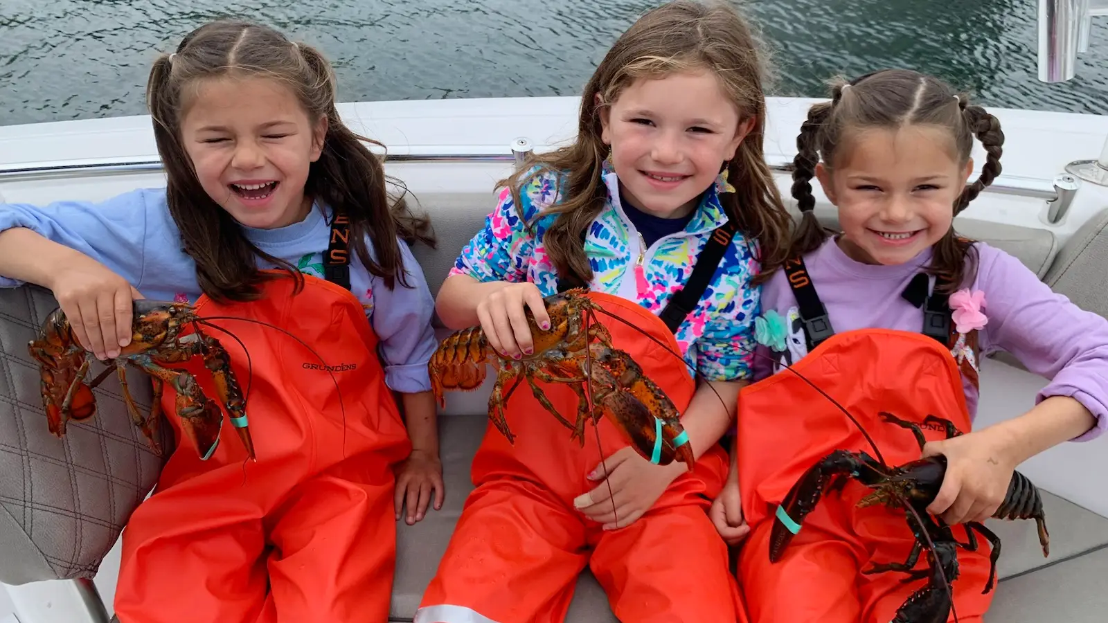 Children holding lobsters on a boat