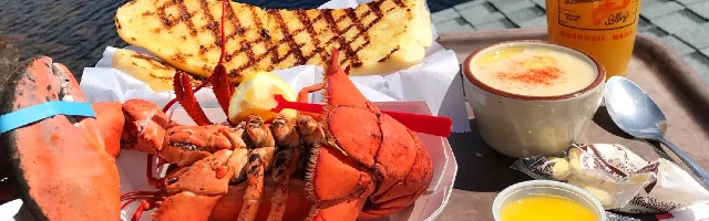 A lobster dinner with steamed lobster, chowder and bread