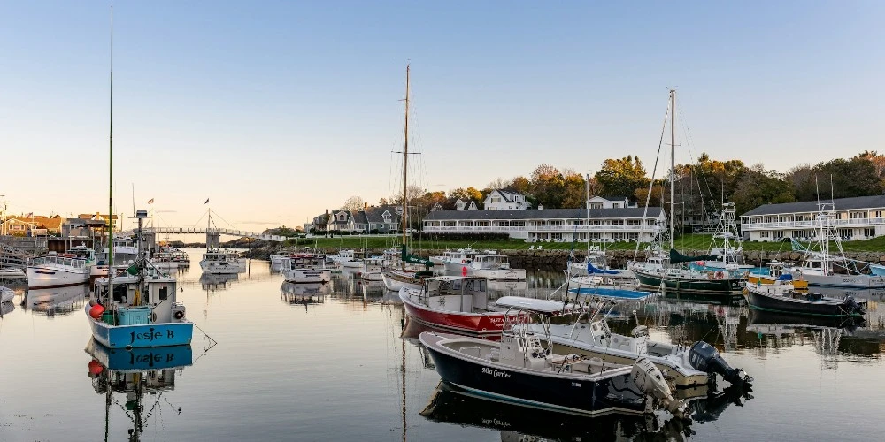 Boats floating in Perkins Cove with the white wooden drawbridge in the background