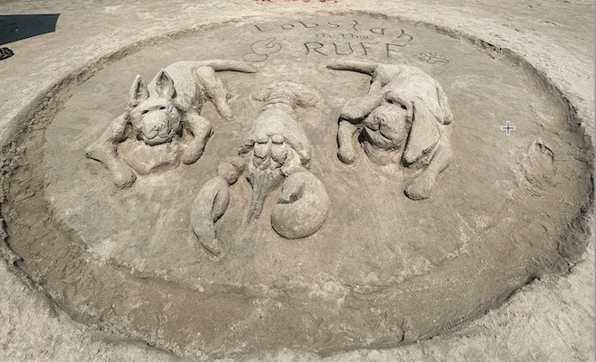 A sandcastle showing a dog and a lobster