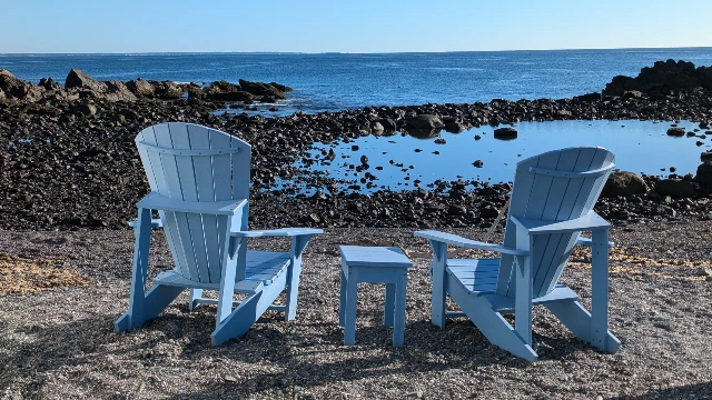 Blue adirondack chairs facing the ocean at Perkins cove.