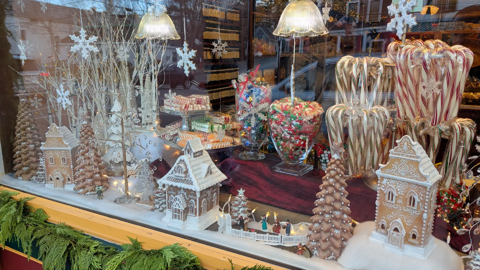 Gingerbread houses and candy canes decorate the window of a candy shop.
